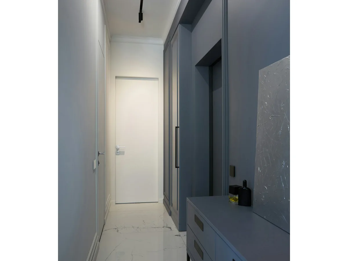 Contemporary grey hallway with flush white slab door and architectural LED track lighting