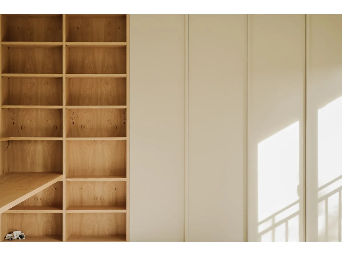 Bespoke pale oak shelving grid with cream slab-panel wardrobe doors and window light